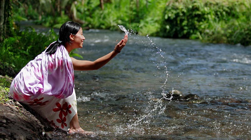 A laughing woman splashing in a river.